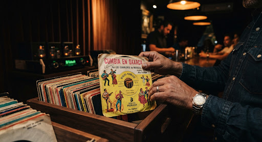 Hands flipping through a wooden crate of vintage 7-inch Latin 45 singles.