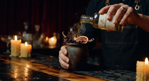 Mezcal poured into a clay copita with orange slice and sal de gusano.