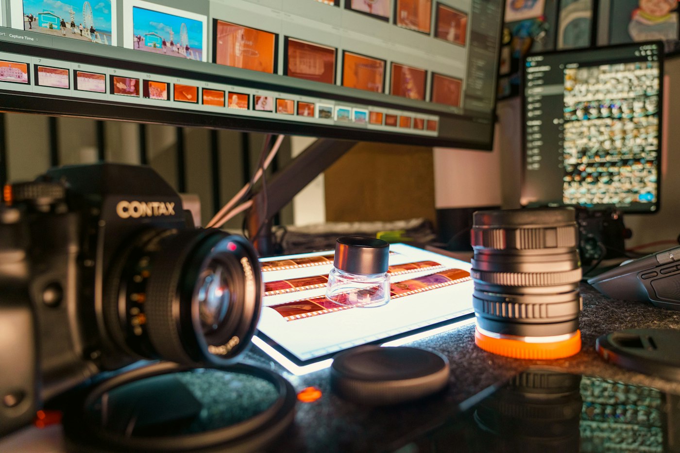 A Contax camera, lenses and film strips on a lit light table