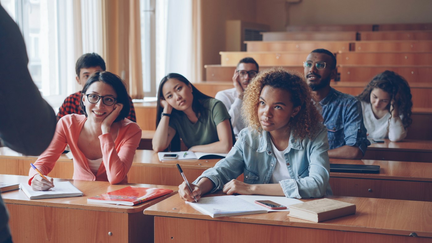 Students filling a tiered lecture hall during a session