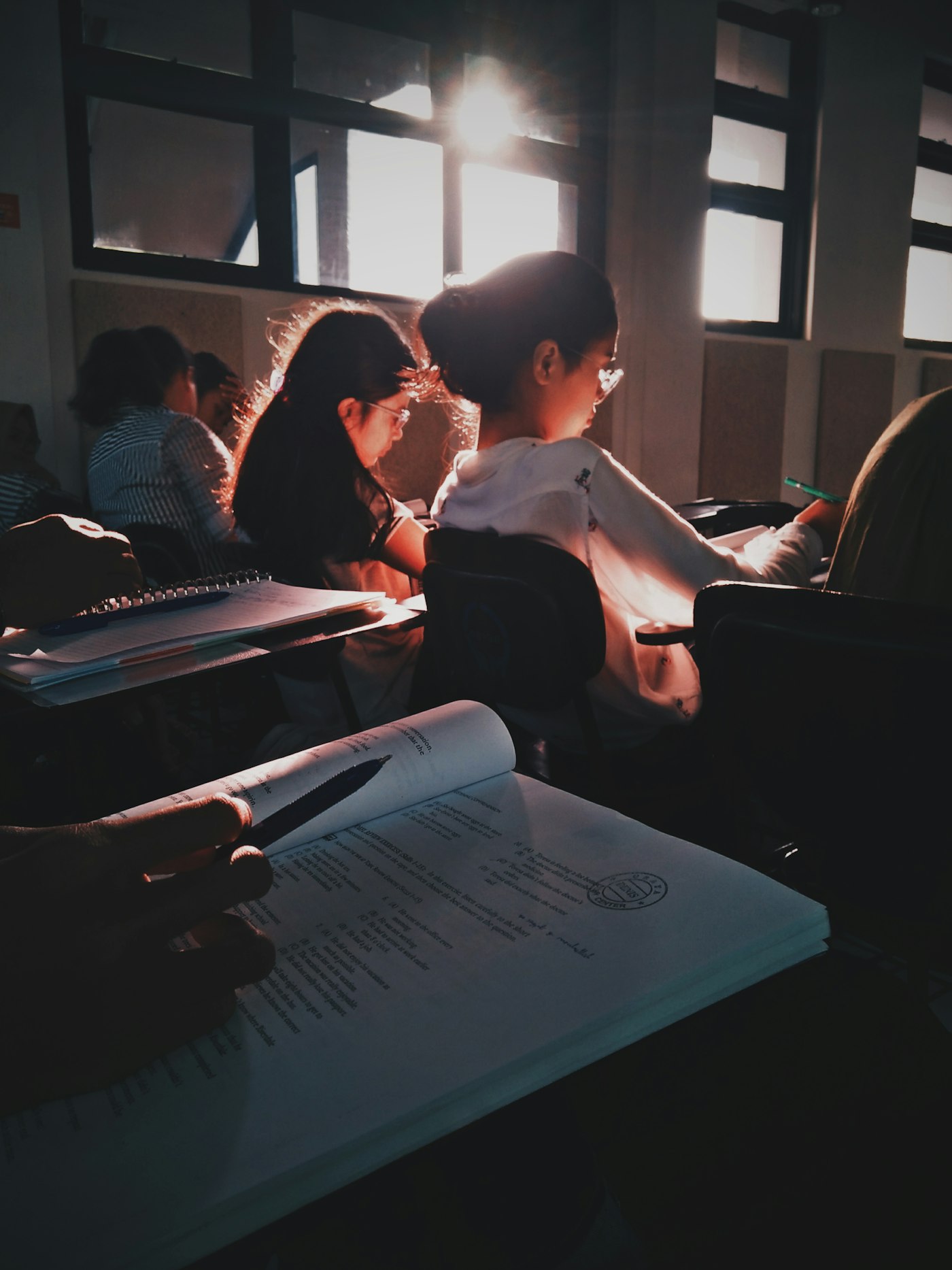 Students working through problem sets in a late classroom lit by low sun