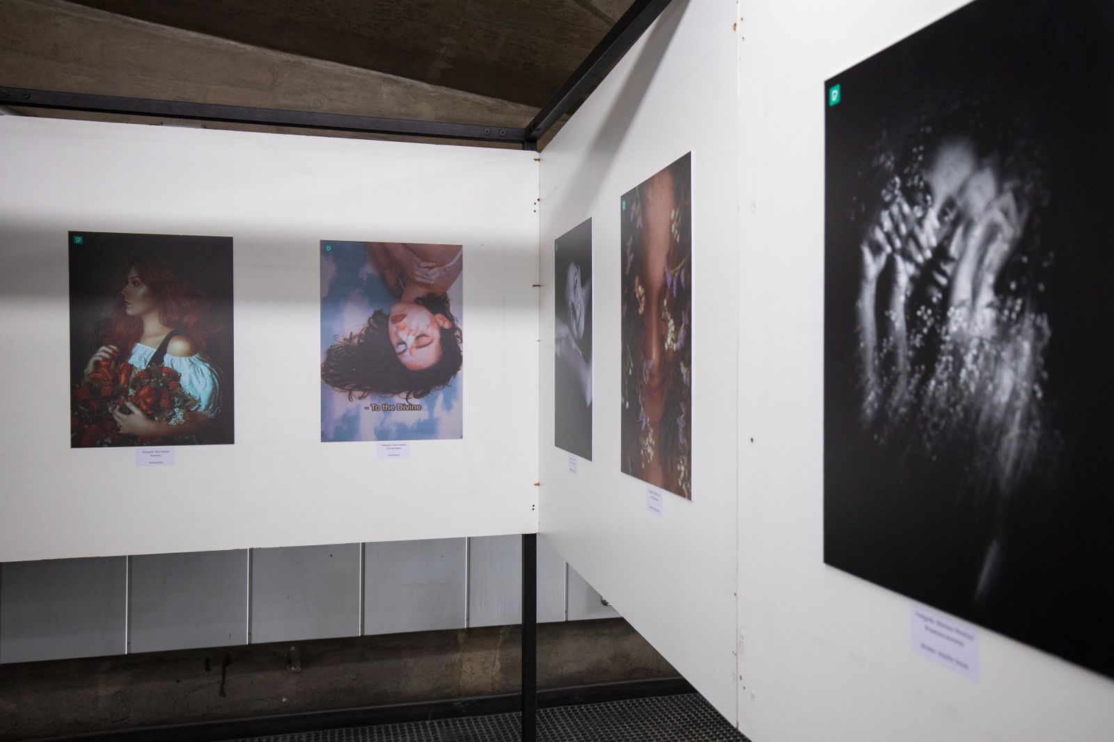 Visitors inside a Designweek exhibition hall with framed prints on white walls