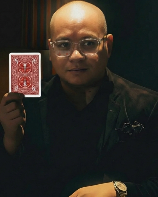 Justin Piñon holding up a playing card.